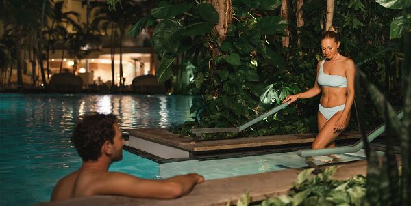 Deux personnes dans le grand lagon de l'oasis de palmiers dans l'ambiance du soir