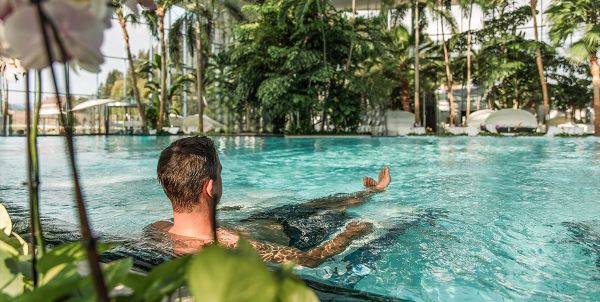 Un homme se détend sur la chaise longue à bulles dans l'oasis de palmiers